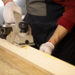 electric planer bevels off wooden workpiece on workbench