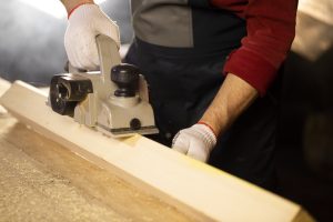 electric planer bevels off wooden workpiece on workbench